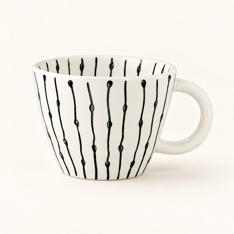 A white ceramic coffee mug with a black vertical drip pattern, shown on a clean white background.