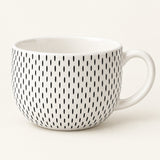 A white ceramic mug with a handle, decorated with a vertical pattern of small black oval marks, shown against a plain off-white background.