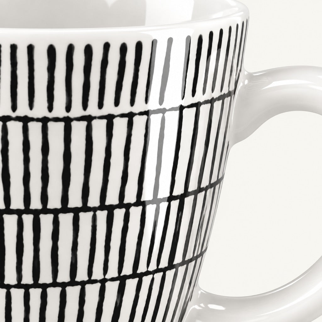 Close-up of a white ceramic mug with a black hand-drawn vertical stripe pattern, showing the side and handle against a light background.