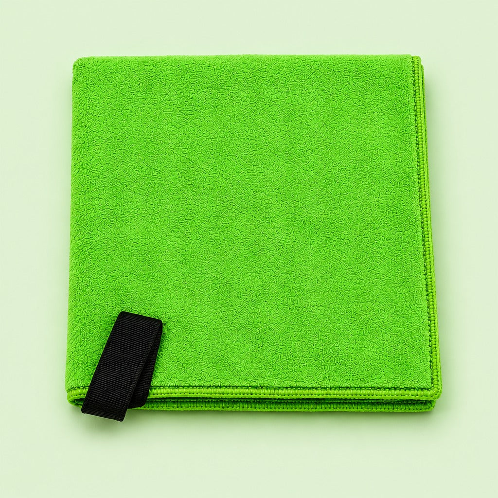 A folded bright green microfiber cleaning cloth with a black strap, shown on a pale mint green background.