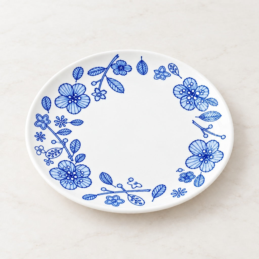 A white oval ceramic plate with a blue floral border pattern, photographed from directly above on a light marble surface.