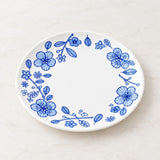 A white oval ceramic plate with a blue floral border pattern, photographed from directly above on a light marble surface.