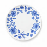 A white ceramic plate with a delicate blue floral border pattern, photographed from directly above on a clean white background.