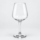 A clear glass wine glass with a wide bowl, slender stem, and flat circular base, photographed on a light gray studio background.
