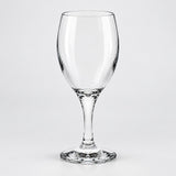 A clear glass wine glass with a wide bowl, a slender stem, and a flat circular base, photographed against a light gray studio background.