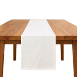 A white fabric table runner centered on a wooden dining table against a plain white background.
