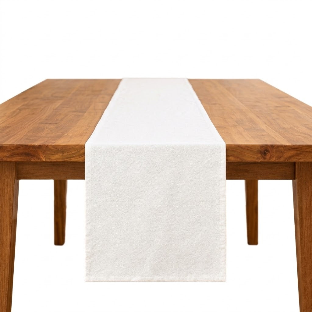 A white fabric table runner centered on a wooden dining table against a plain white background.