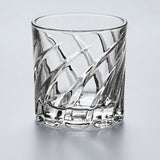 A clear cut-crystal whiskey glass with a diagonal diamond pattern and a thick ribbed base, shown on a light gray reflective surface.