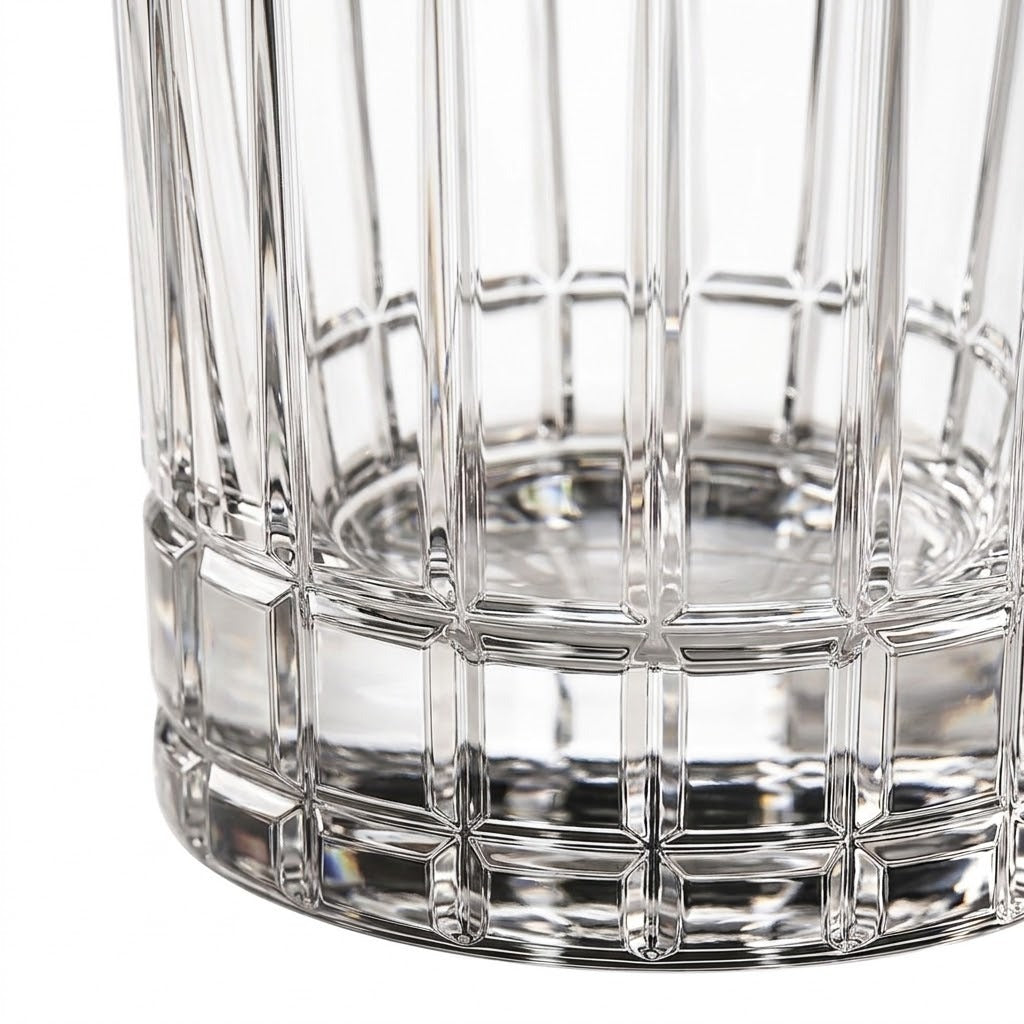 Close-up of a clear cut-glass tumbler with a flared base and vertical faceted pattern on a white background.