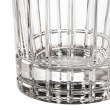 Close-up of a clear cut-glass tumbler with a flared base and vertical faceted pattern on a white background.