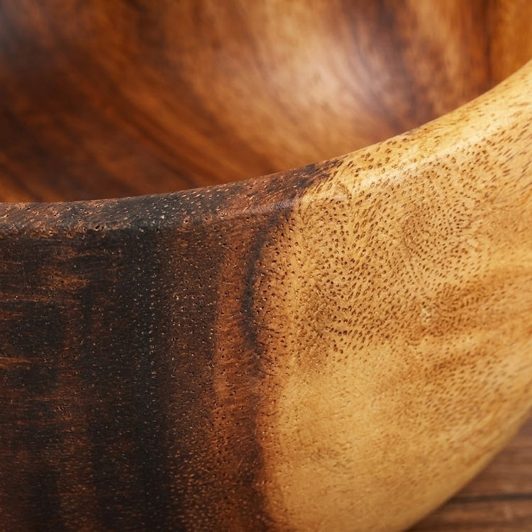 Close-up of a wooden bowl showing a natural wood grain transition from dark brown to light tan.