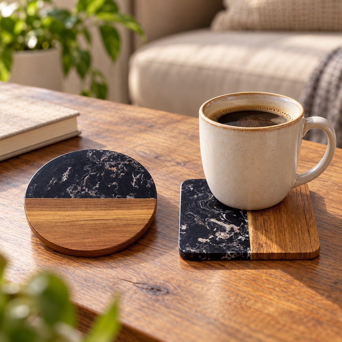 Two round coasters with a black marble top half and natural wood bottom half, shown on a wooden table with a white ceramic mug filled with coffee in one and resting flat on the other.