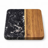 A square serving board or tray with rounded corners, featuring a split design: one half is black marble with white veining, and the other half is smooth medium-brown wood grain, shown on a white background.