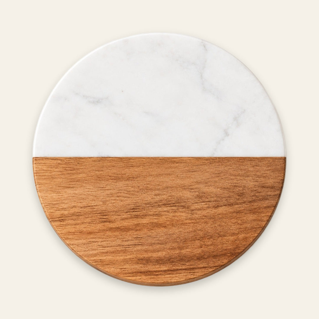 A round serving board or tray with a split design, featuring a white marble top half and a warm brown wood grain bottom half, centered on a light cream background.