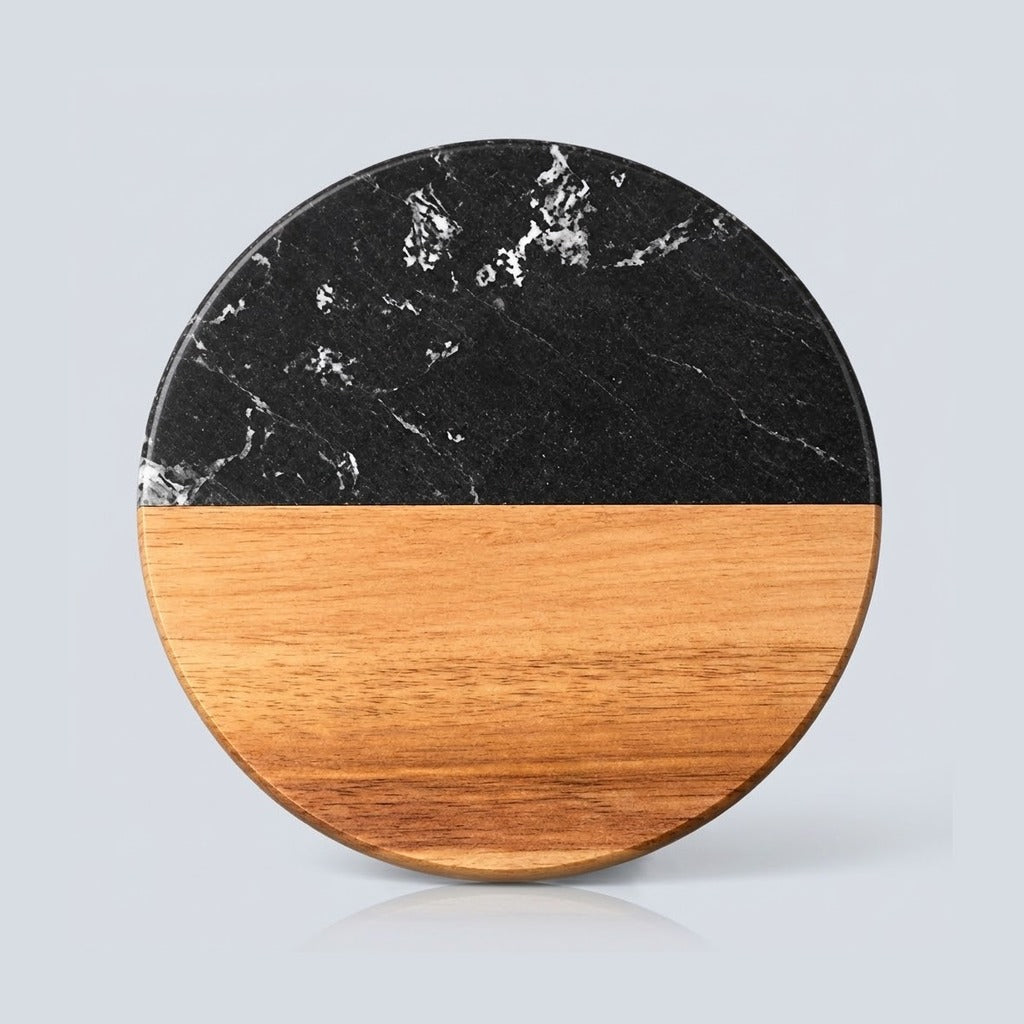 A round split-design coastertop or trivet made of black marble on the top half and natural wood on the bottom half, shown on a light gray background.