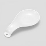 A white ceramic spoon rest with a hanging hole at the handle, photographed on a light gray background.