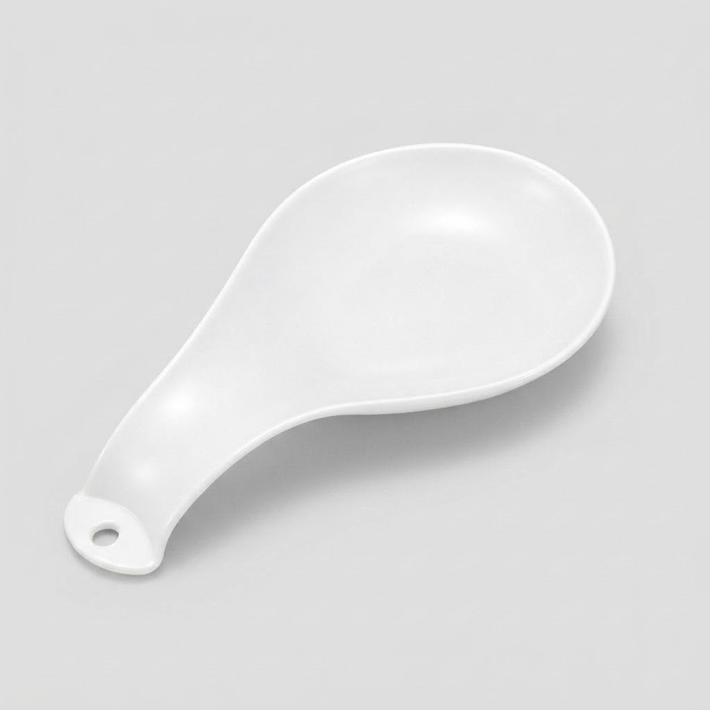 A white ceramic spoon rest with a hanging hole at the handle, photographed on a light gray background.