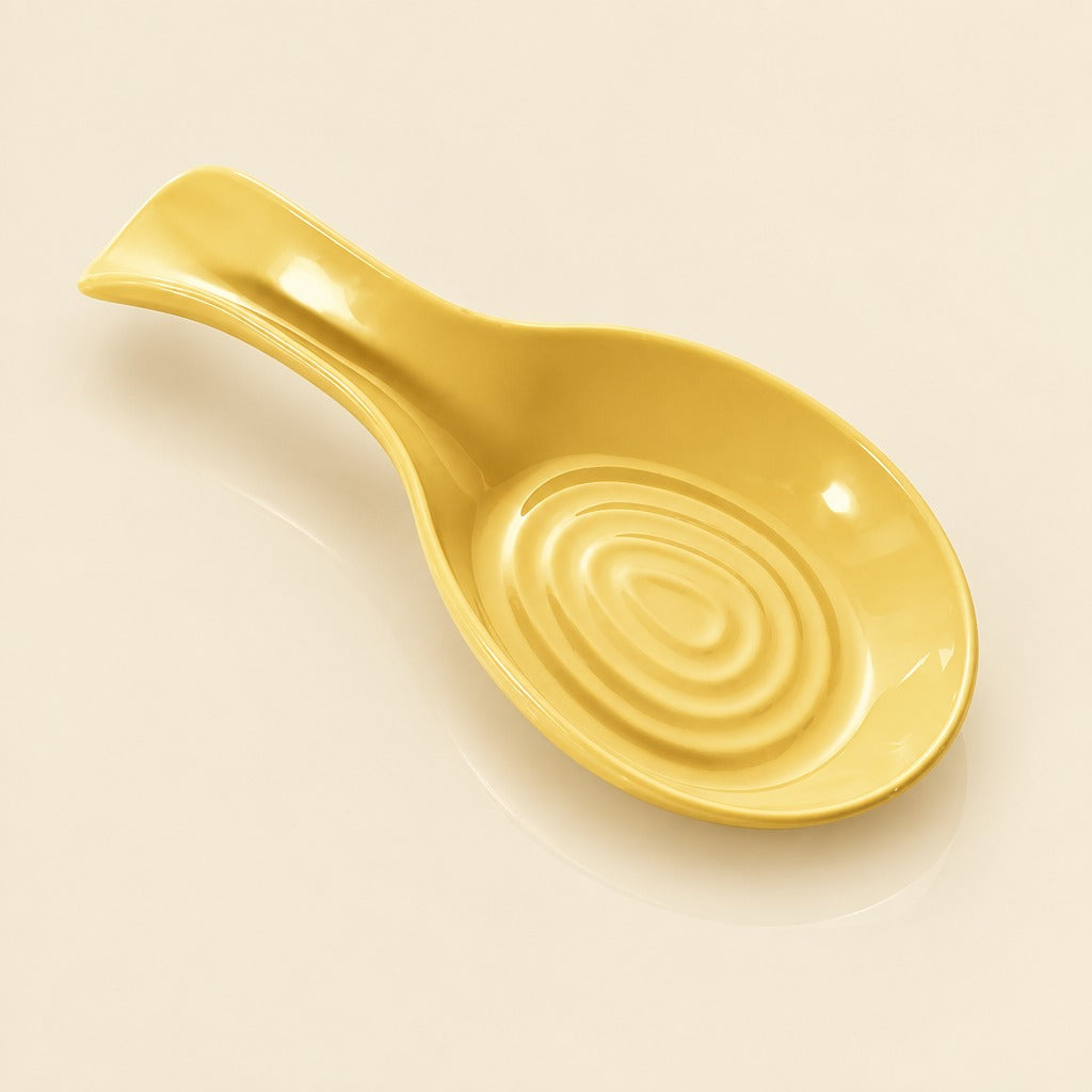 A glossy yellow ceramic spoon rest with a spiral pattern inside the bowl and a curved handle, shown on a light cream background.