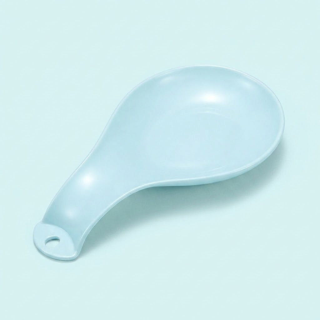 A light blue ceramic spoon rest with a hanging hole, photographed on a matching pale blue background.