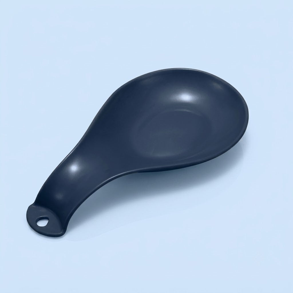A matte black silicone or rubber spoon rest with a hanging hole at the handle, shown on a light gray background.