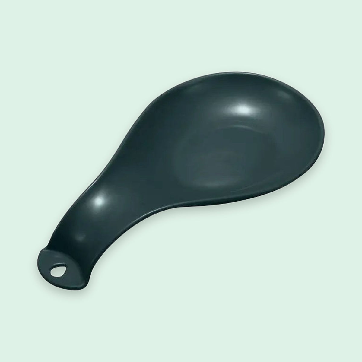 A matte black ceramic spoon rest with a hanging loop at the handle, shown on a pale mint green background.