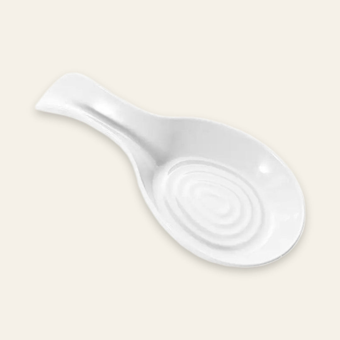 A white ceramic spoon rest with a spiral pattern in the center and a handle on the left, shown on a solid light beige background.