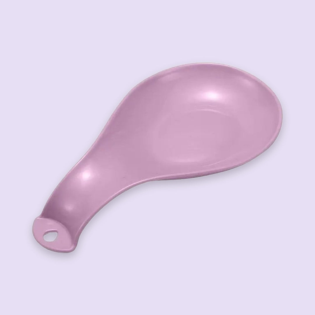 A single pink plastic spoon or scoop with a hanging hole at the handle, shown on a plain light lavender background.