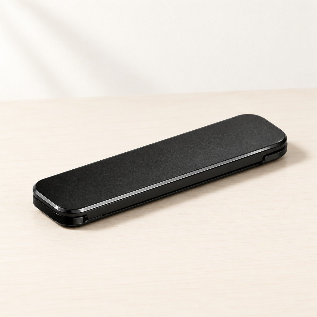 A sleek black rectangular electronic device, possibly a power bank or portable charger, resting diagonally on a light beige wooden surface against a white background.