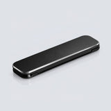 A sleek, rectangular black case with rounded corners and a brushed metal silver edge, shown closed on a light gray reflective surface.