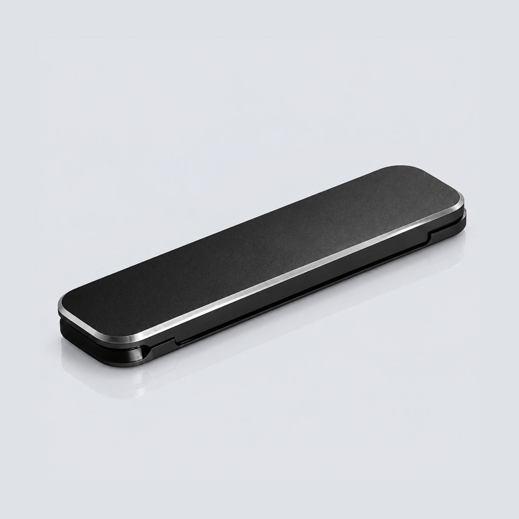 A sleek, rectangular black case with rounded corners and a brushed metal silver edge, shown closed on a light gray reflective surface.