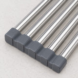 Close-up of a set of stainless steel rod handles with dark gray square end caps, arranged diagonally on a light textured surface.