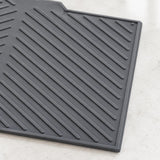 A dark gray rubber kitchen mat with diagonal ridges, shown on a light marble countertop.