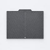 A black rubber or plastic protective cover with a textured diagonal ribbed pattern and a small circular hole near the bottom center, shown flat against a light gray background.
