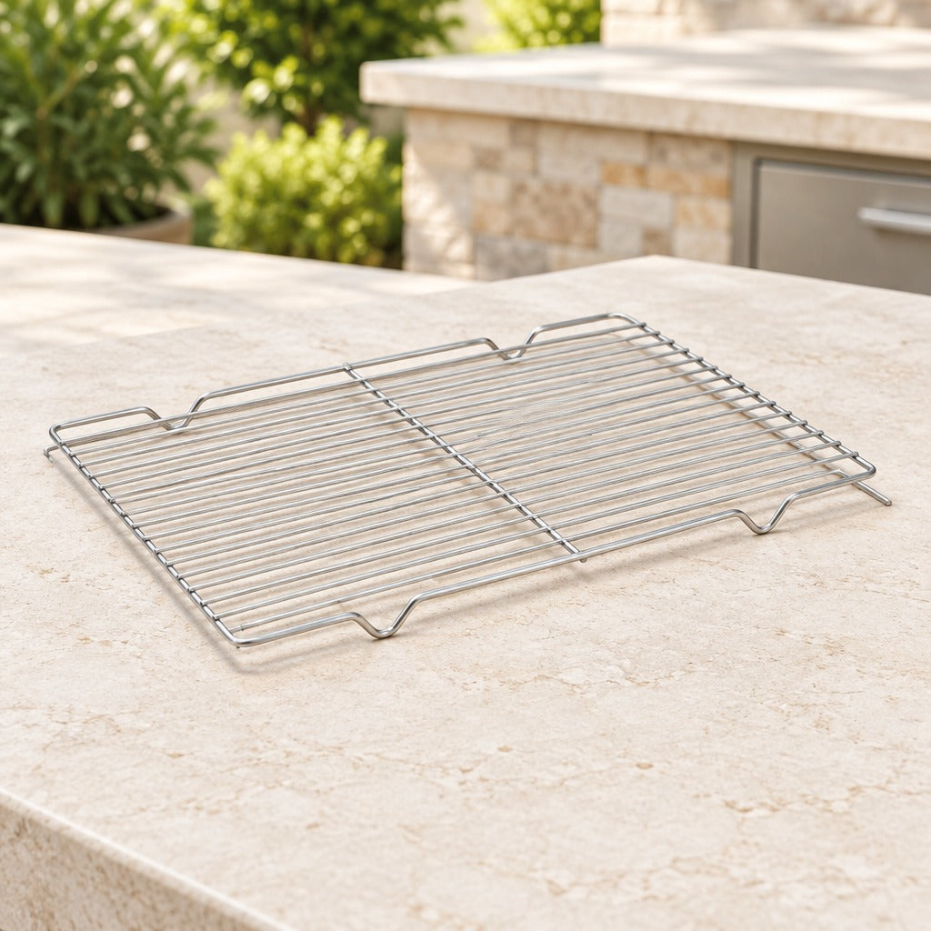 A rectangular stainless steel wire cooling rack with integrated handles, shown on a beige stone countertop outdoors with a blurred kitchen or patio background.