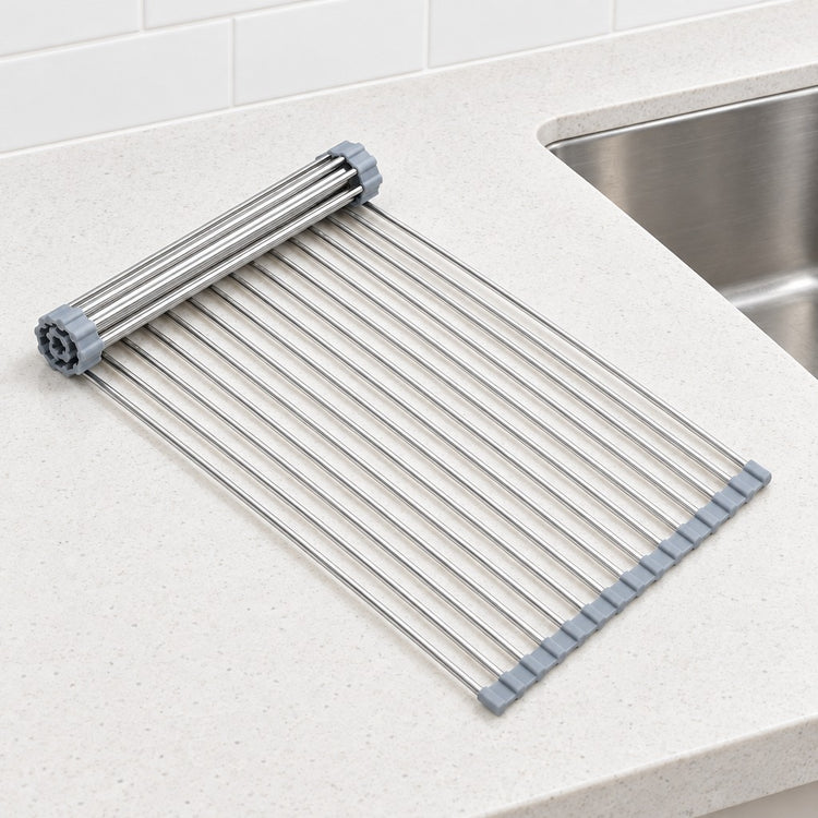 A stainless steel kitchen drying rack with gray plastic end caps, shown on a light speckled countertop next to a sink.