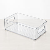 A clear plastic storage bin with integrated side handles and a slotted bottom tray, shown on a light wood surface against a white background.