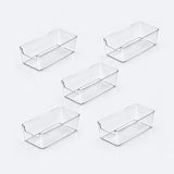 Five clear plastic rectangular storage bins arranged on a light gray reflective surface.