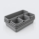 A set of five gray plastic storage containers in nested rectangular and square shapes, arranged on a clean white background.