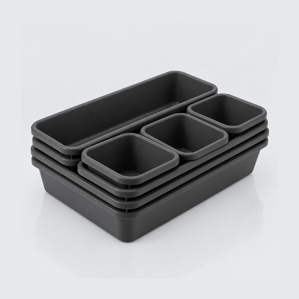 A set of five black plastic storage containers with nested compartments, arranged in a stack on a light gray reflective surface.
