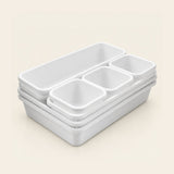 A stack of white plastic organizer bins with one large rectangular compartment and four smaller square compartments, shown on a light beige background.