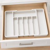 A white drawer organizer tray with multiple vertical divider slots, shown inside an open wooden drawer.