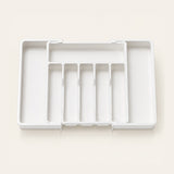 A white plastic multi-compartment organizer tray with five vertical slots, shown open on a light beige background.