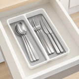 A white plastic drawer organizer tray with a gray insert, holding a set of stainless steel cutlery inside an open white drawer.