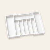 A white plastic organizer tray with five vertical compartments, shown open on a light beige background.
