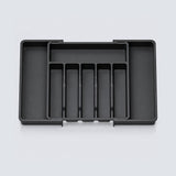 A black plastic cash organizer tray with multiple compartments, shown from a top-down view on a light gray background.