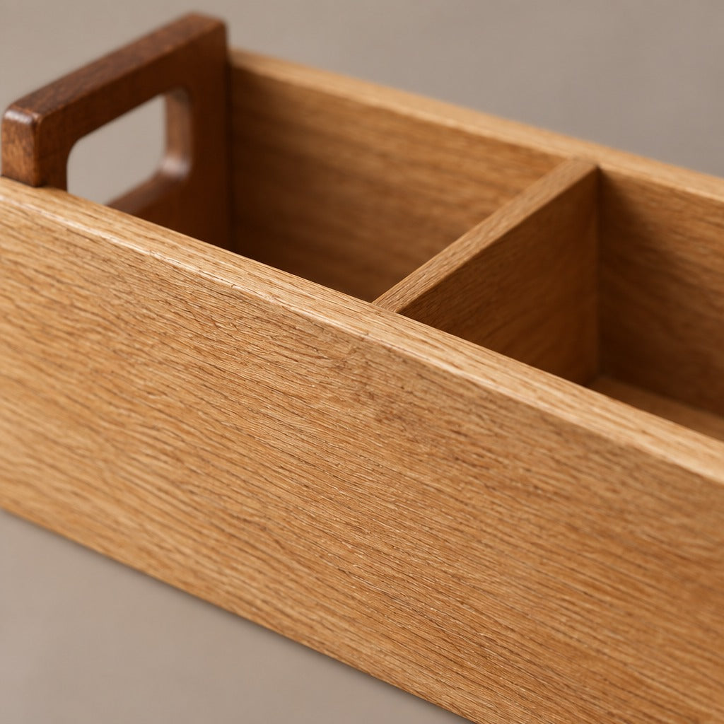 Close-up of a wooden organizer tray with a warm honey oak finish, featuring a rectangular handle cutout on one end and a two-compartment divider.