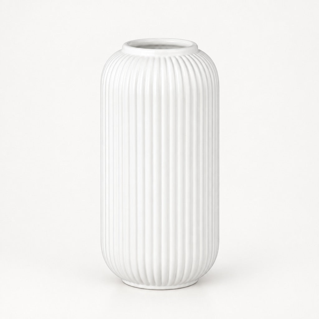A white ceramic vase with a ribbed, vertically fluted texture, standing on a clean white background.