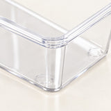 Clear plastic storage bin with transparent walls and rounded corners, shown close-up on a light beige surface.