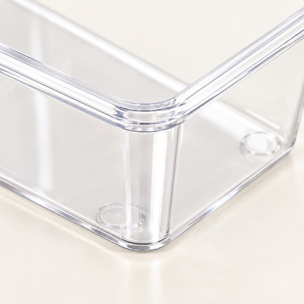 Clear plastic storage bin with transparent walls and rounded corners, shown close-up on a light beige surface.