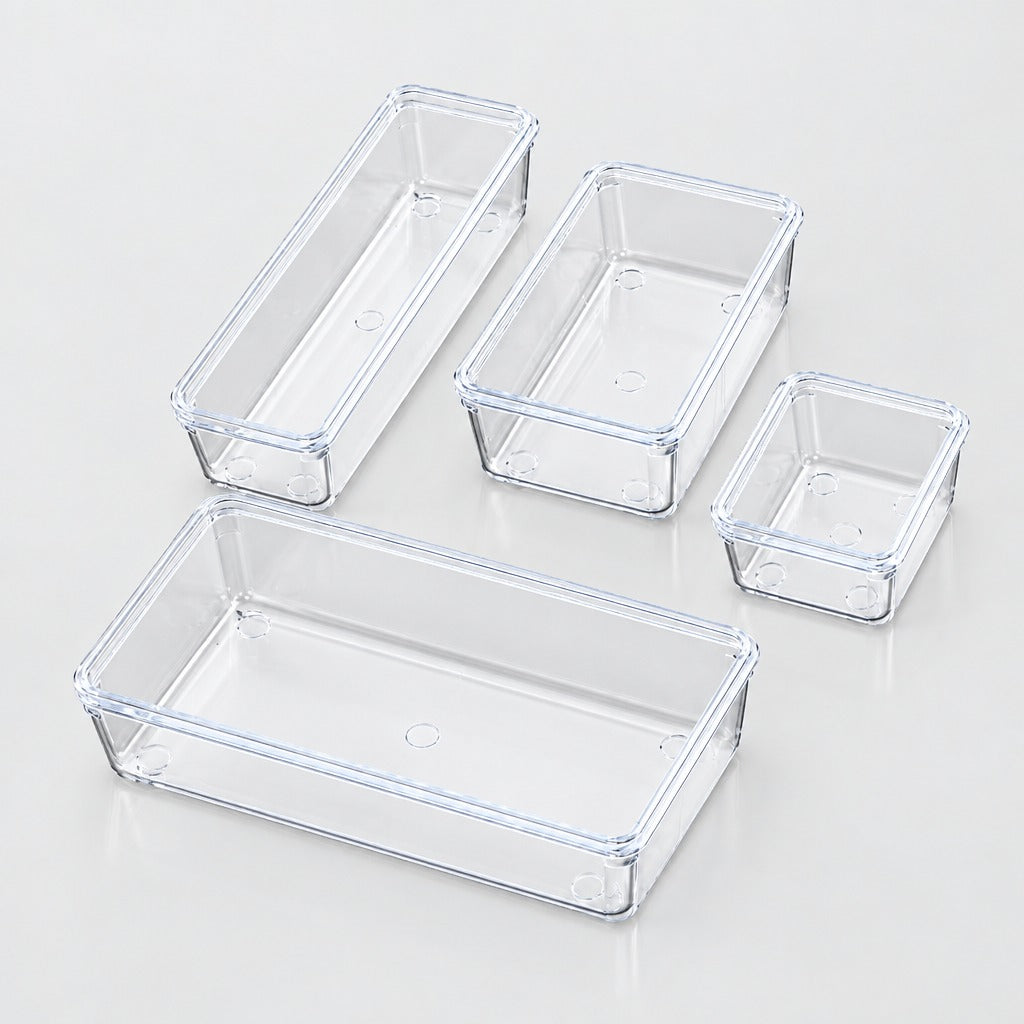 Four clear plastic rectangular storage bins in different sizes arranged on a light gray reflective surface.